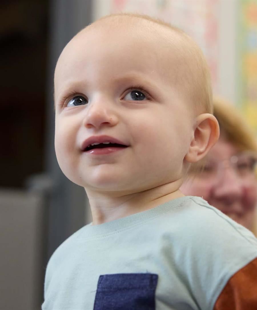 Close-up of a smiling young child with a light blue shirt.